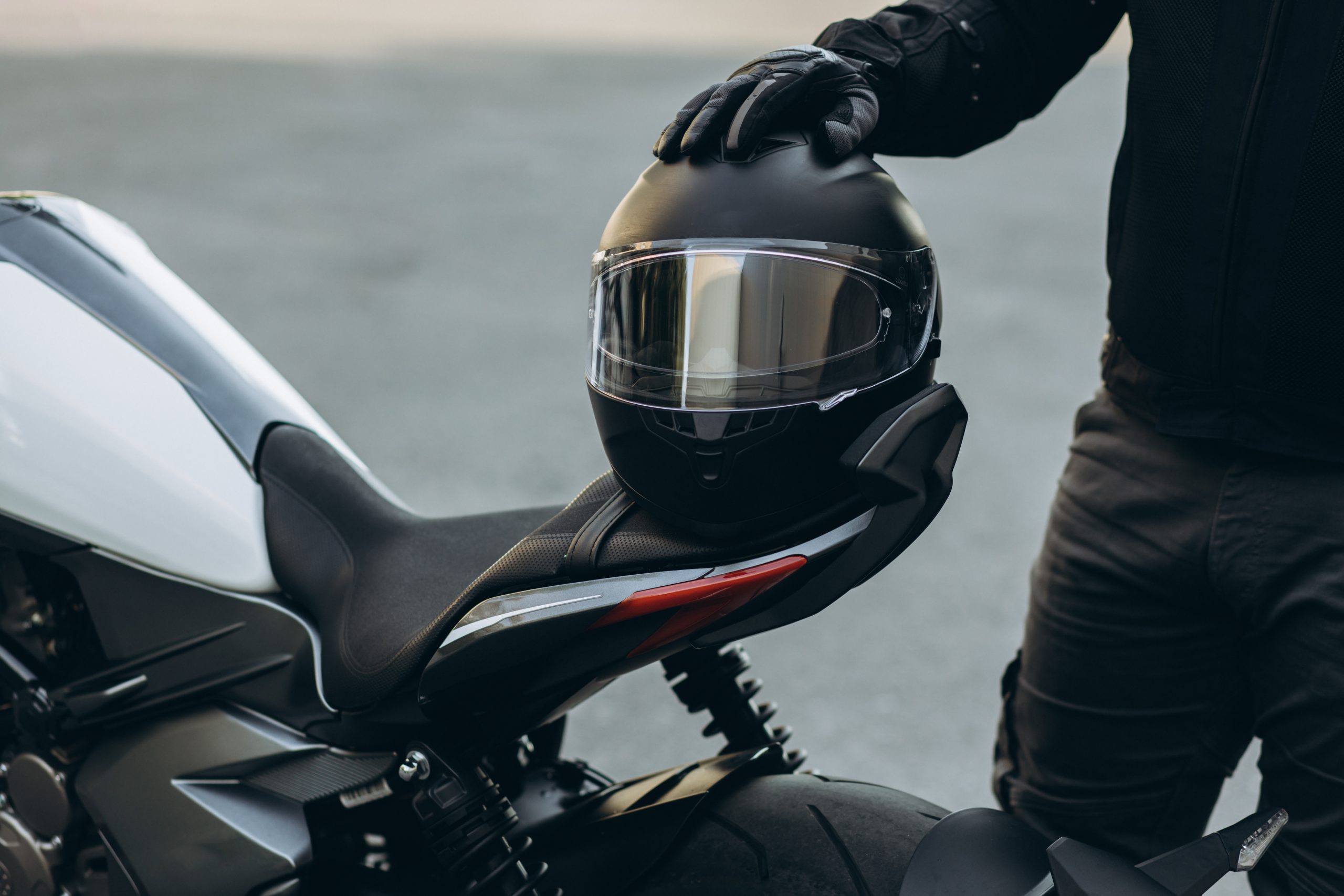 hombre-motociclista-pie-junto-su-motocicleta-sosteniendo-su-casco-scaled