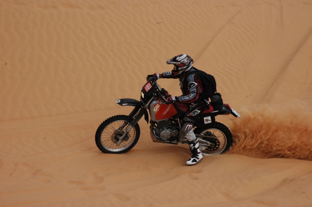 Piloto subido a una moto en una de las ediciones del Rally Dakar. Fuente: iStock / leonardodesign21